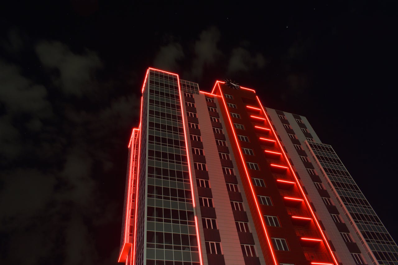 A striking view of a skyscraper with red neon lights against a night sky.